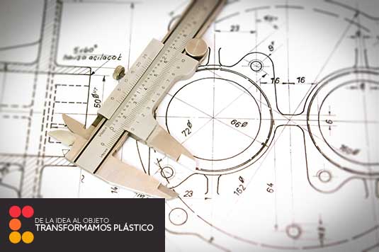Acercamiento de una laptop con planos detrás y una pluma.